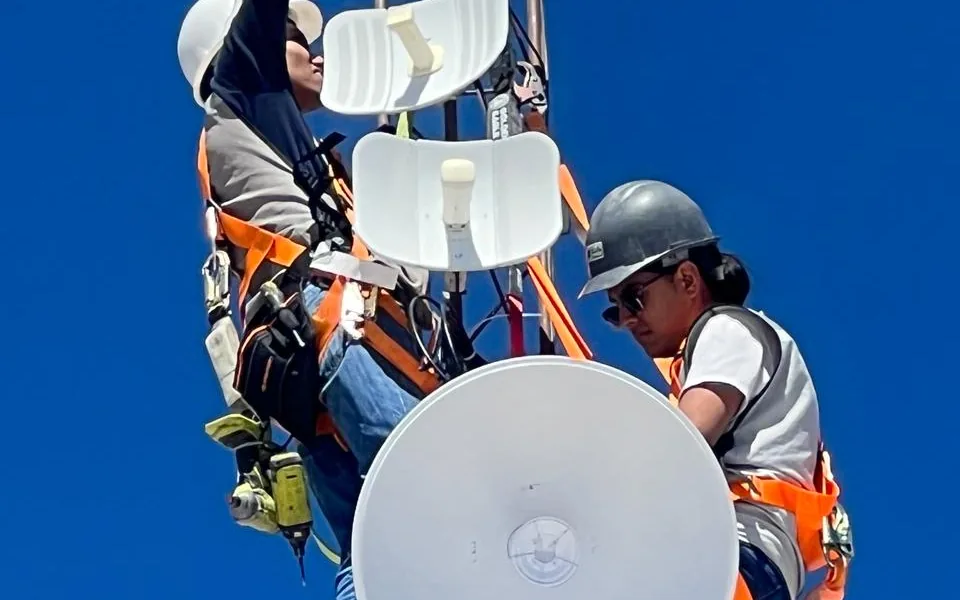 Técnicos instalando antenas de enlace inalámbrico en lo alto de una torre